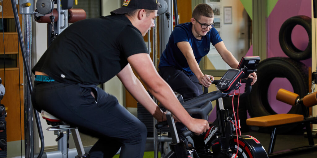 Photo of two students using exercise bikes in a gymnasium