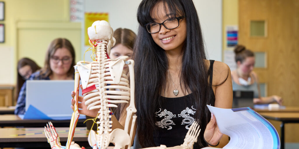 Photo of students working in a classroom environment and a student looking at a model of a skeleton