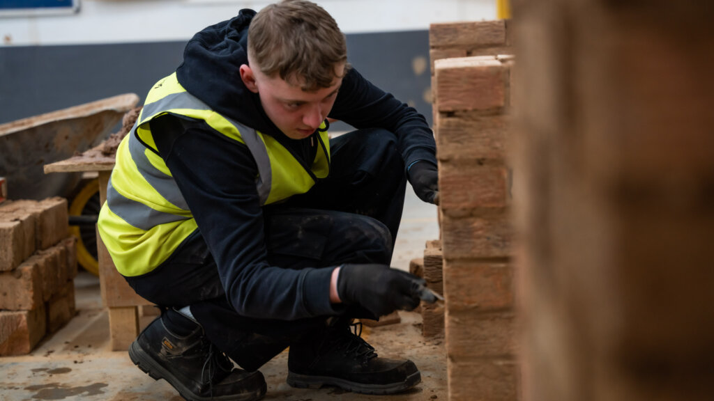 A bricklaying student building a wall