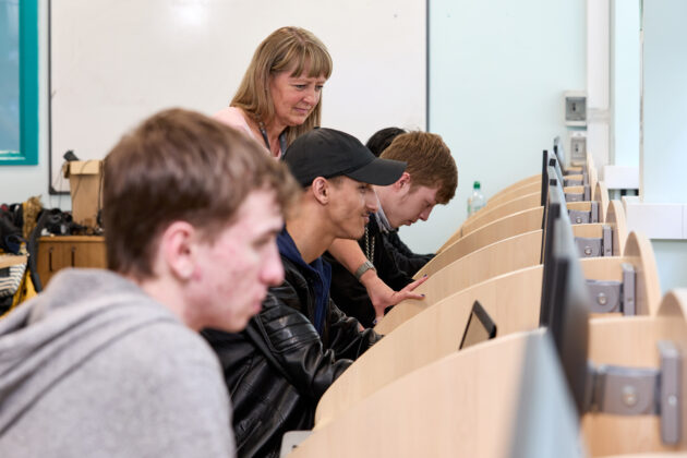 students using computers with tutor assisting