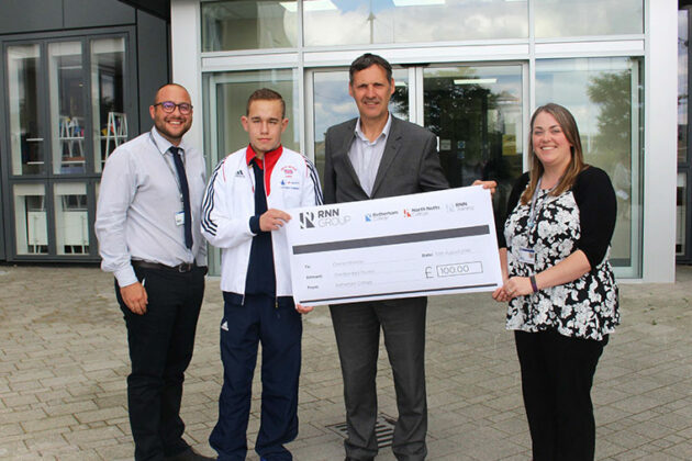 Connor stands with members of staff holding his sponsorship cheque.