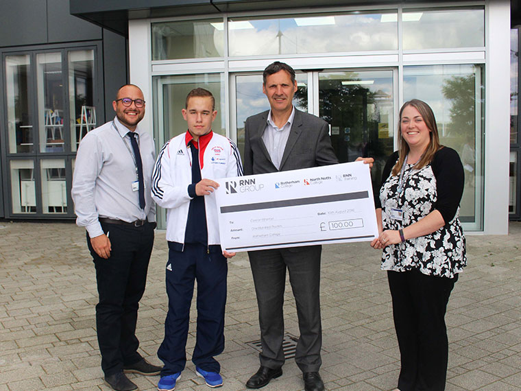 Connor stands with members of staff holding his sponsorship cheque.