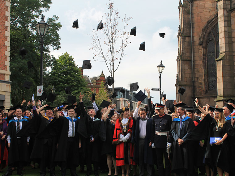 Students celebrate graduation by throwing their caps into the air.
