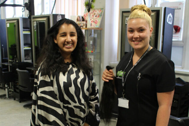A student stands next to hairdressing student.