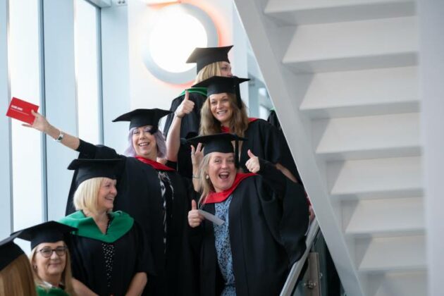 Graduates waving at the photographer on the stairs at one of our graduation ceremonies.