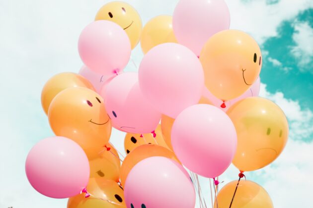 pink and orange balloons with happy and sad faces