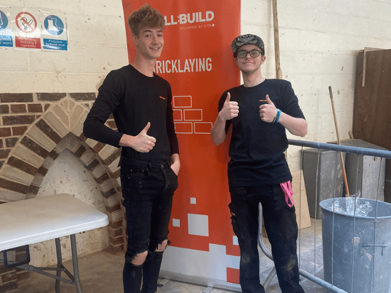Two bricklaying students giving thumbs up