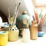 Paint pots and brushes next to a window