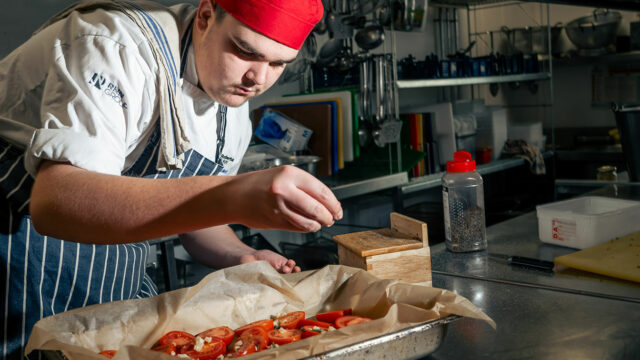 A catering student preparing food in the kitchen
