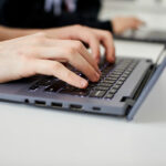 A close up of hands typing using a laptop