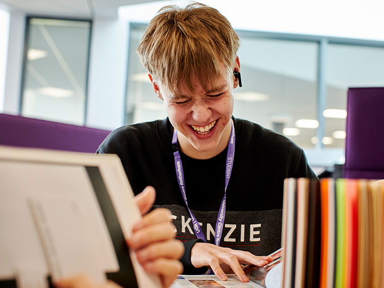 A student sat at a table laughing with their peers