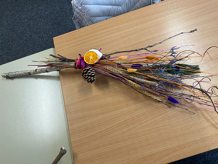 An arrangement of long twigs and dried flowers arrange in a bunch on a table